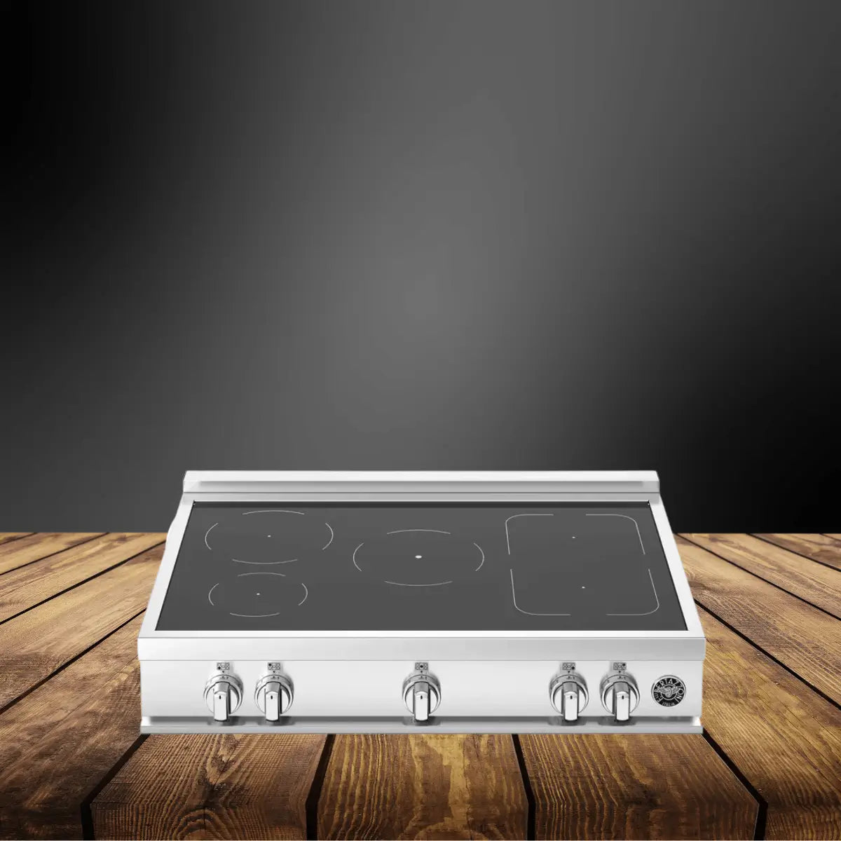 Electric rangetop with smooth glass cooktop surface and front control knobs in a stainless steel finish, displayed on a wooden countertop with a dark modern background.